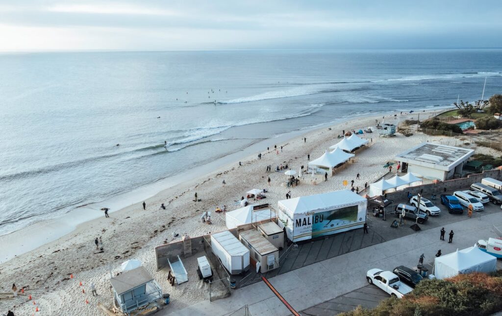Aerial shot of a beach in Malibu featuring tents and people enjoying the coastal scenery.