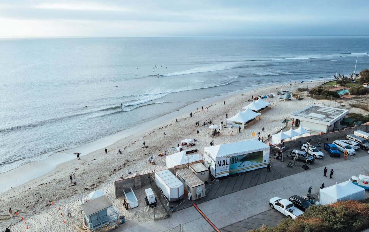 Aerial shot of a beach in Malibu featuring tents and people enjoying the coastal scenery.